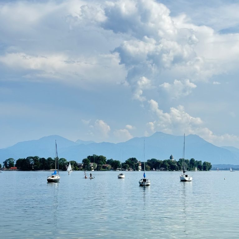 Wunderschöne Kulisse am Chiemsee mit Segelbooten und Blick auf die Fraueninsel